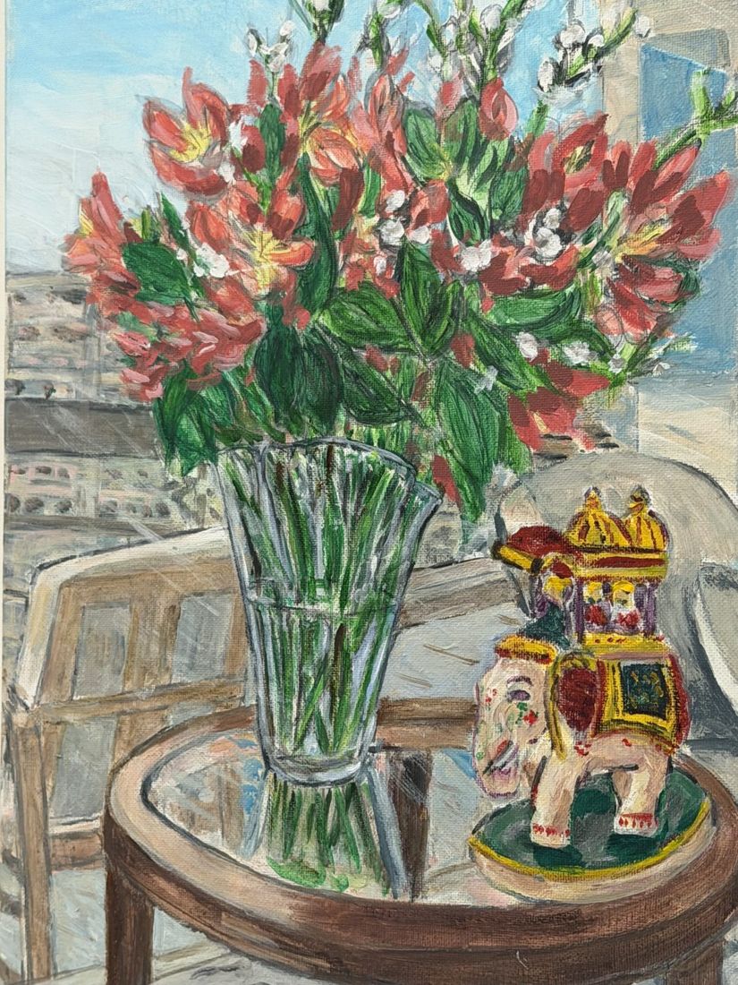 Painting of red lilies in a glass vase beside an ornamental elephant