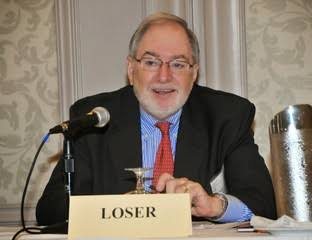Claudio Loser seated at a panel table behind a name card